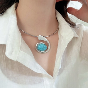 Close-up of silver collar necklace featuring a large oval turquoise pendant in a sleek frame
