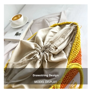 Close-up of beige drawstring inner lining on a yellow and orange woven straw handbag