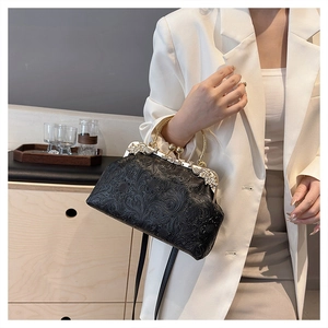 Detail of vintage black embossed shell bag with gold handle and diamond clasp worn by model