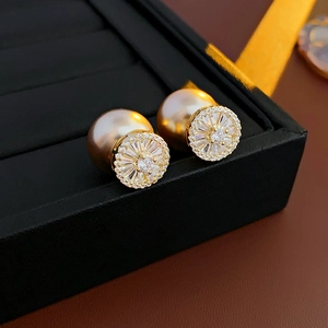 Macro shot of gold plated pearl earrings with zircon inlay in a premium jewelry box