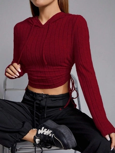 Detail of burgundy ribbed knit crop top featuring side drawstring and hooded design