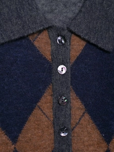 Detail of argyle knit polo collar with mother-of-pearl buttons in blue and brown