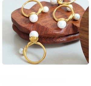 Detailed close-up of French-style twisted gold rings with colorful inlaid pearls on wood