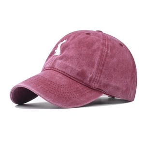 Dettaglio del ricamo a coniglio bianco sul cappellino da baseball bordeaux in cotone
