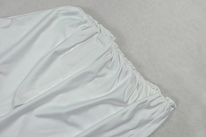 Detail of white dress showing elastic ruched waistline and soft textured fabric
