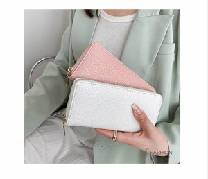Close-up of pink and white long zip-around wallets featuring textured lychee grain leather