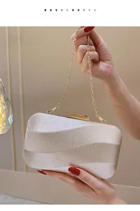 Close-up of champagne gold evening clutch with wavy texture and gold chain strap