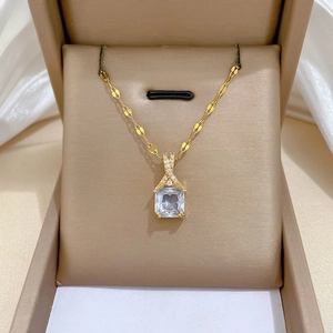 Macro view of gold plated necklace with rectangular zircon pendant and olive leaf chain