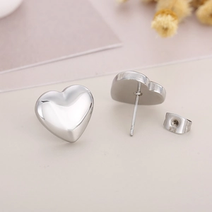 Close-up of heart-shaped silver stud earrings with 925 hallmarks on a floral background