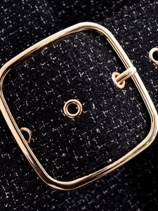 Detail of black tweed fabric texture and shiny golden square metal belt buckle