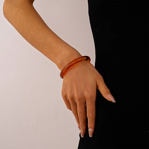 Detail shot of amber translucent acrylic ring bracelet on wrist with high-end texture