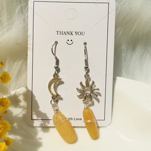 Macro detail of sun and moon stainless steel earrings with handmade wire-wrapped yellow stones
