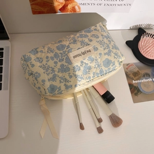 Close-up of a soft quilted floral cosmetic bag with blue flowers and makeup brushes