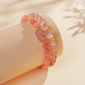 Dettaglio del bracciale in quarzo fragola con ciondolo a gatto e accenti corona dorata