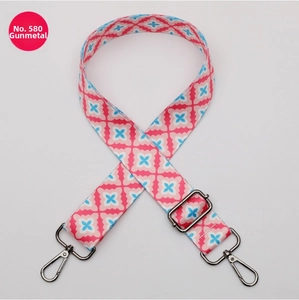Detail of wide adjustable polyester bag strap with pink floral pattern and gunmetal hardware