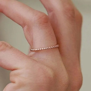Dettaglio dell'anello con perline minimalista in oro rosa indossato al dito