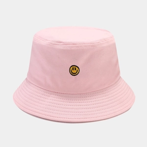 Close-up of the yellow smiley face embroidery on a pink cotton outdoor bucket hat