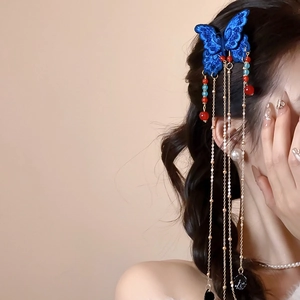 Détail de la pince à cheveux papillon bleu brodé avec pompon doré sur tresse