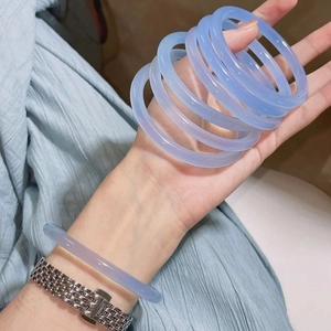 Detailed view of semi-transparent ice-blue agate chalcedony bangles on a woman wrist