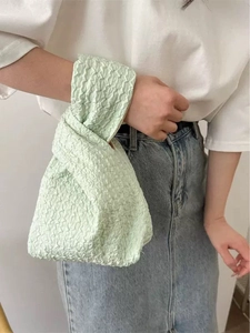 Detail shot of pale green knotted wrist bag with soft pleated canvas fabric texture