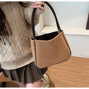 Close-up of brown teddy fleece tote bag with leather handle held by model in interior