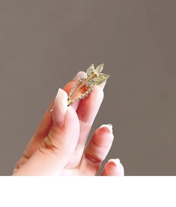 Detailed view of a gold-plated carrot brooch featuring orange and green crystal stones