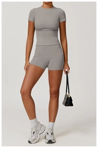 Detailed view of grey short sleeve crop top and high waist sports shorts on a fitness model