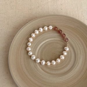 Detailed shot of Baroque pearl and pink gemstone bracelet on a beige ceramic plate