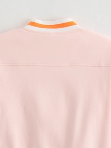 Detailed view of pink jacket collar with white and orange striped ribbed knit trim