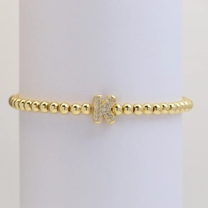 Detail of gold beaded elastic bracelet featuring a micro-paved cubic zirconia letter K charm