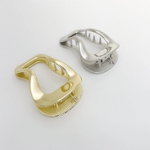 Close-up of golden and silver irregular wave hair clips with woven mesh texture
