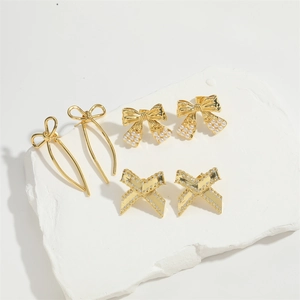 Three pairs of elegant gold bow earrings with pearls and micro zircons on a stone tray