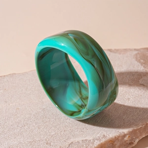 Detail of wide marble pattern resin bangle on stone, showing teal ink textures