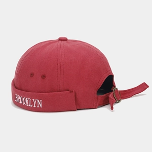 Detail of red canvas docker cap showing white Brooklyn embroidery and adjustable strap