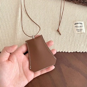 Detail of brown faux leather key case necklace featuring white contrast stitching