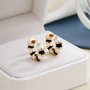 Close-up of black and white enamel striped hoop earrings in a cream jewelry box