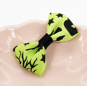 Close-up of lime green Halloween bow with black star patterns on pink ceramic plate