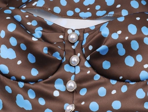 Macro detail of satin dress with blue polka dots and elegant pearl buttons with silver trim