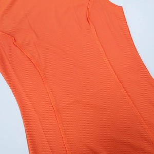 Close-up of the orange ribbed knit fabric texture and high-quality seam stitching detail