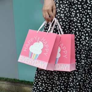 Pink paper gift bag with cute cupcake and rainbow prints featuring sturdy rope handles