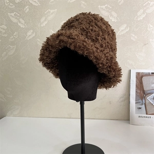 Detail of dark brown faux shearling bucket hat with warm curly plush texture on a model
