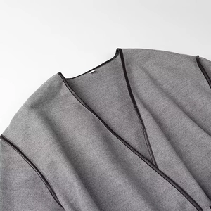 Close-up of gray wool coat showing fine fabric texture and black leather piping detail