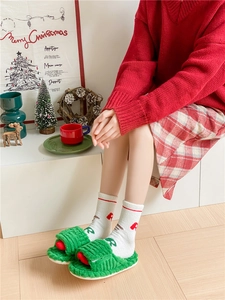 Cozy green Christmas plush slippers and patterned socks in a festive holiday home setting