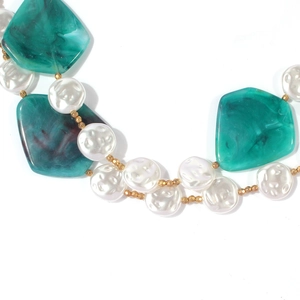 Detail of green irregular resin pieces and white faux pearls on a gold-tone necklace