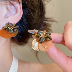 Detail of vintage flower stud earrings with tiger eye stone and shell petals worn by model