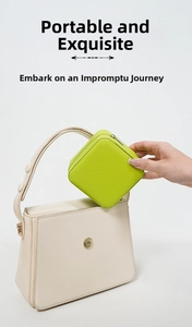 Mini lime green jewelry travel case being placed into a handbag for portable storage
