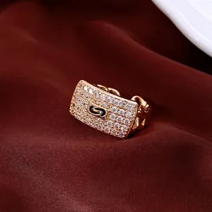 Golden rectangular zircon ring with chain band design on elegant red silk background