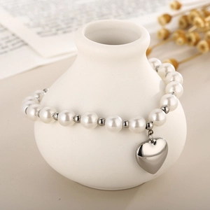 Détail d'un bracelet en perles avec séparateurs argentés et pendentif cœur sur vase
