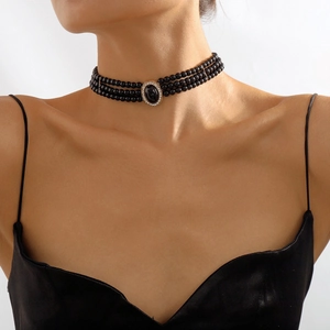 Detail of three-layer black beaded necklace with oval gemstone on a female model