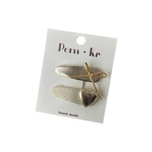 Golden heart and bow hair clips set on white card with handmade labeling